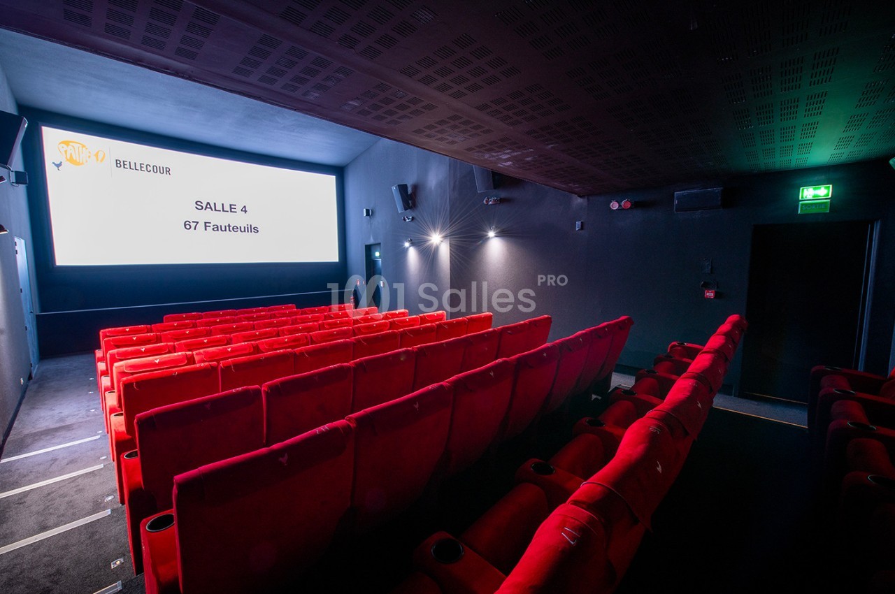 Salle de cinéma avec des rangées de fauteuils rouges, écran blanc affichant ’Salle 4 - 67 Fauteuils’.