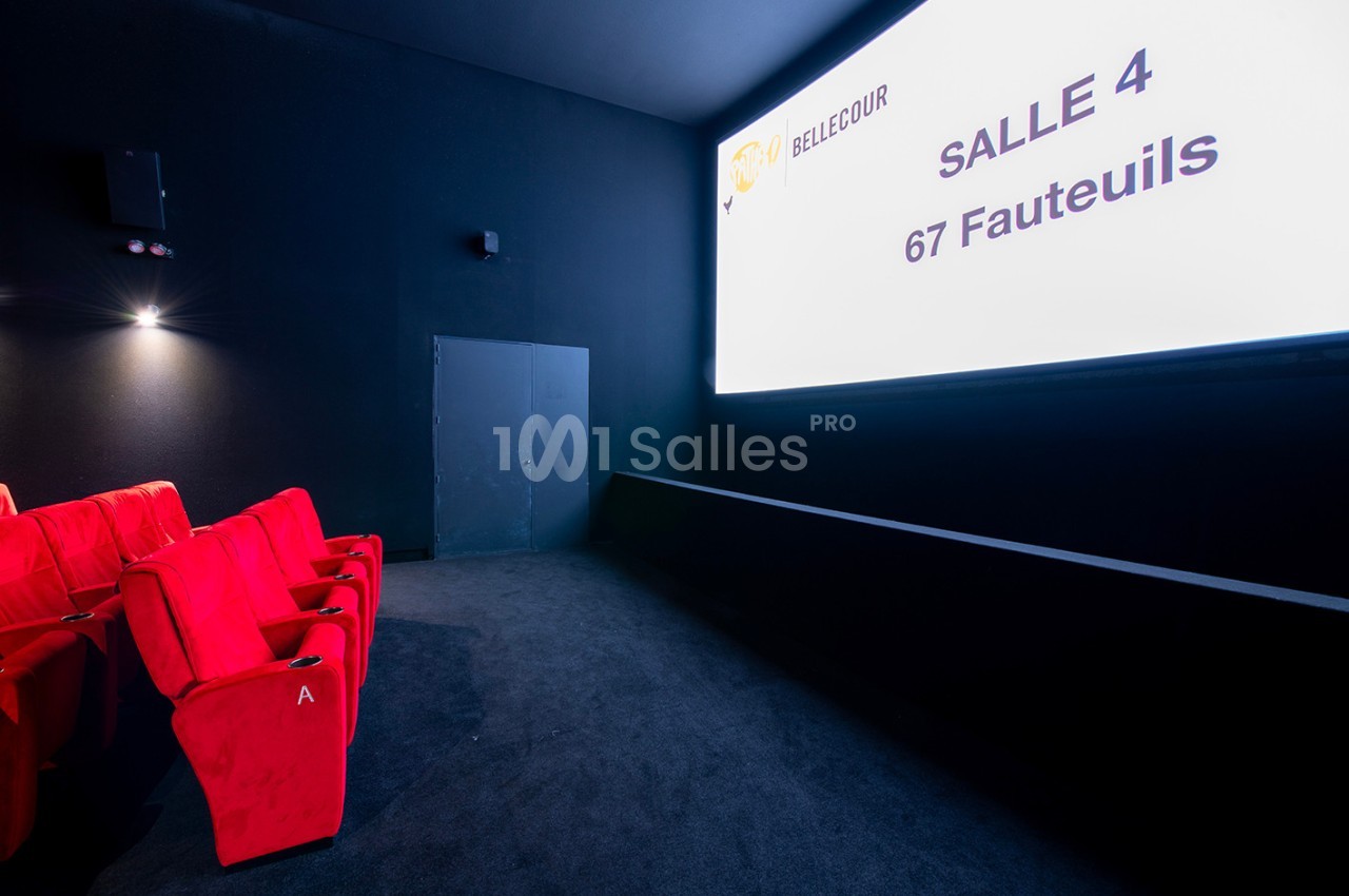Salle de cinéma avec écran blanc, rangée de fauteuils rouges et indication ’Salle 4 - 67 Fauteuils’ sur l'écran.