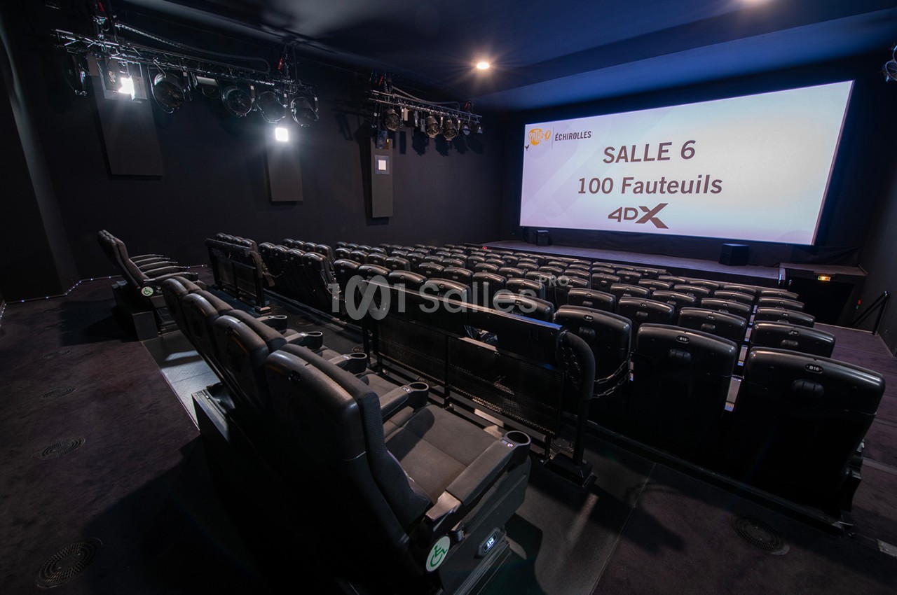 Salle de cinéma équipée de fauteuils 4DX, avec écran allumé et éclairage tamisé.