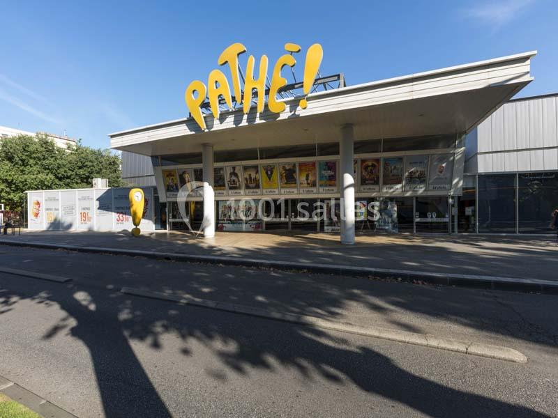 Façade d'un cinéma Pathé avec affiches de films en vitrine, sous un ciel bleu clair.