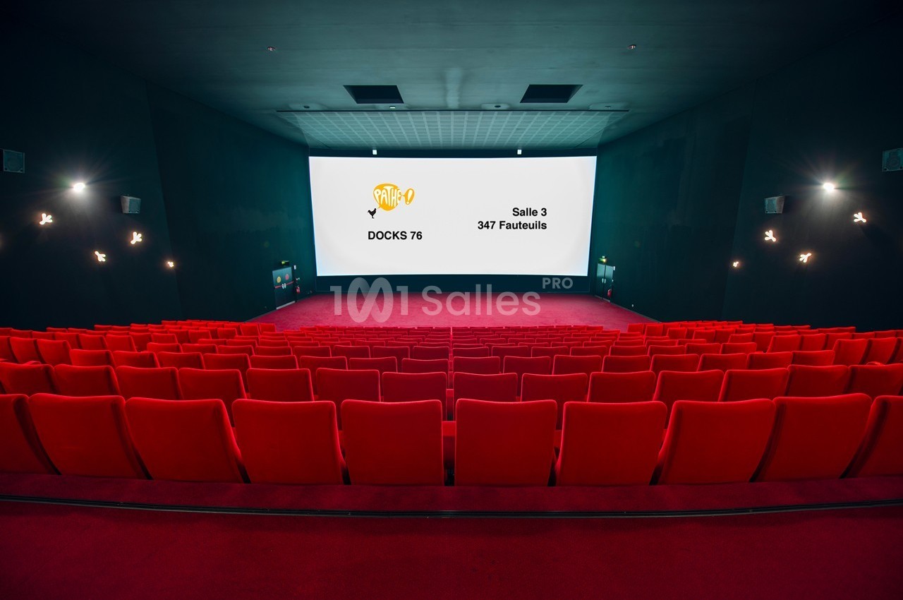Salle de cinéma vide avec des rangées de fauteuils rouges et un écran affichant des informations sur la salle.