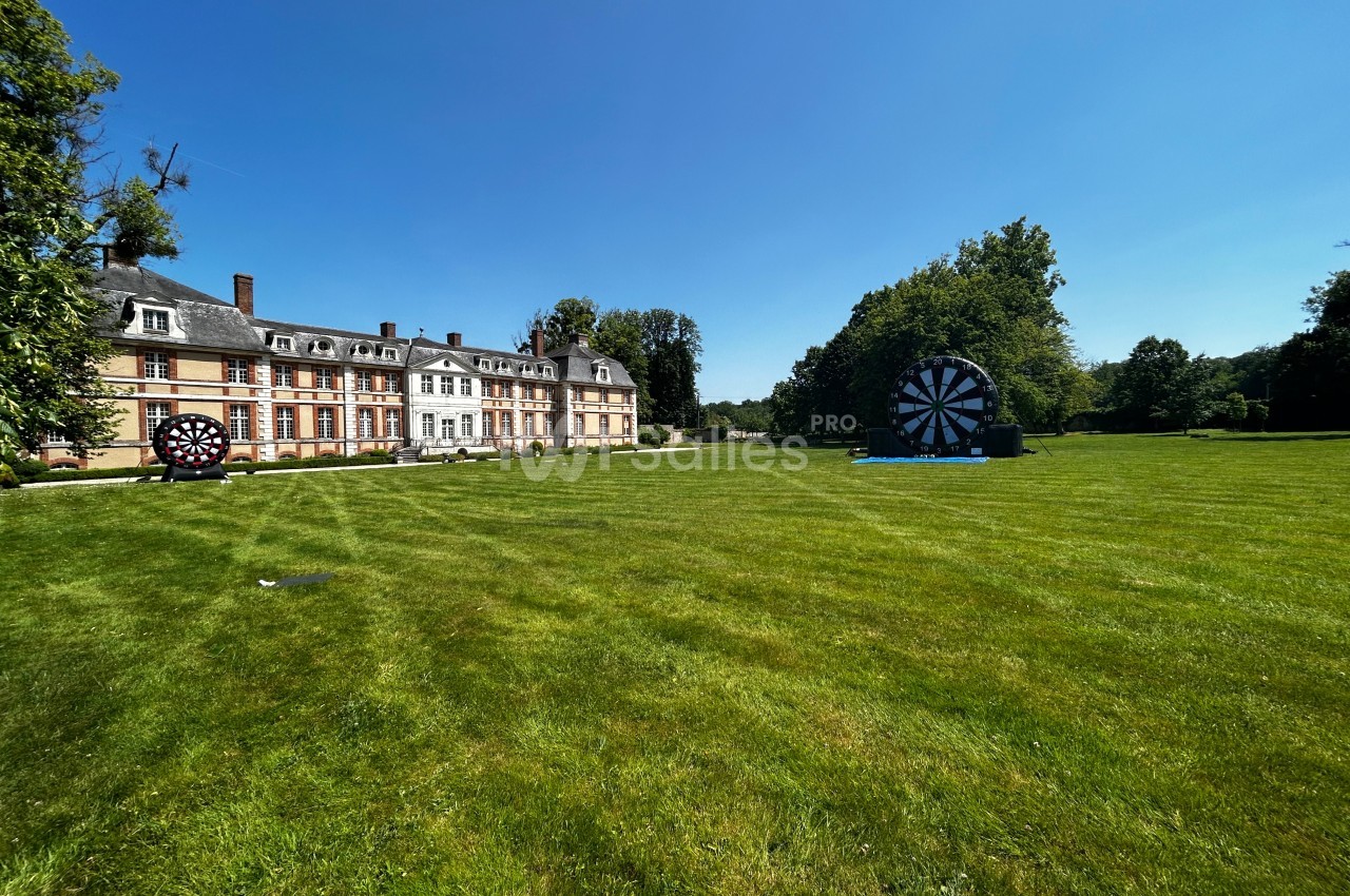 Pelouse verdoyante devant un château avec des cibles géantes installées sur le terrain par temps ensoleillé.