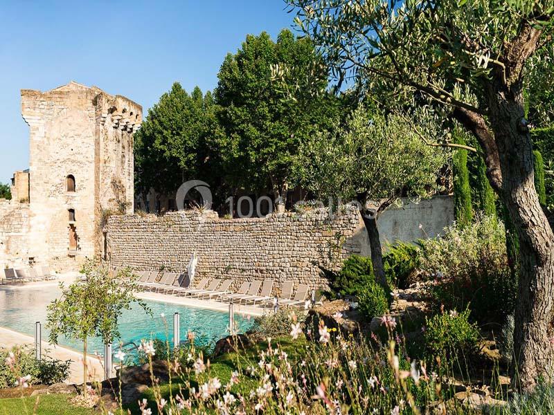 Ruines historiques près d'une piscine entourée de végétation et de chaises longues sous un ciel dégagé.