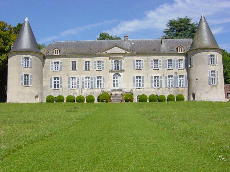 Château ancien avec deux tours rondes, façade symétrique et pelouse verdoyante au premier plan.