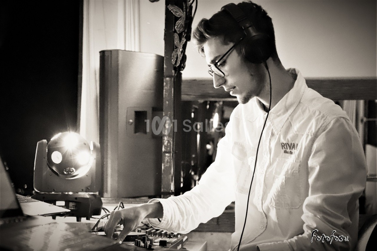 Un homme portant un casque audio mixe de la musique sur une table de mixage dans un environnement faiblement éclairé.