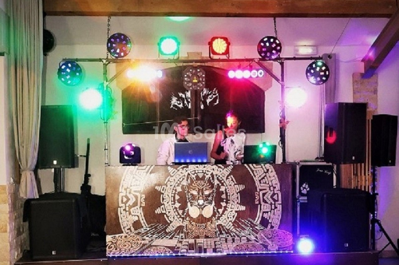 Deux DJ mixant sur une scène décorée, entourée de lumières colorées et d'équipements audio.
