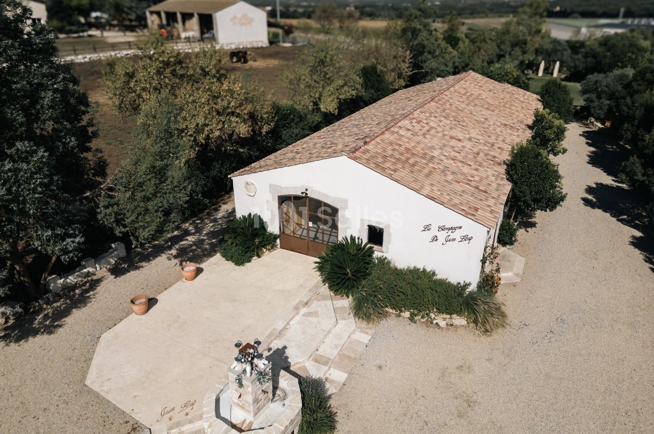 Bâtiment en pierre avec toit en tuiles, entouré de végétation, situé dans un environnement rural.