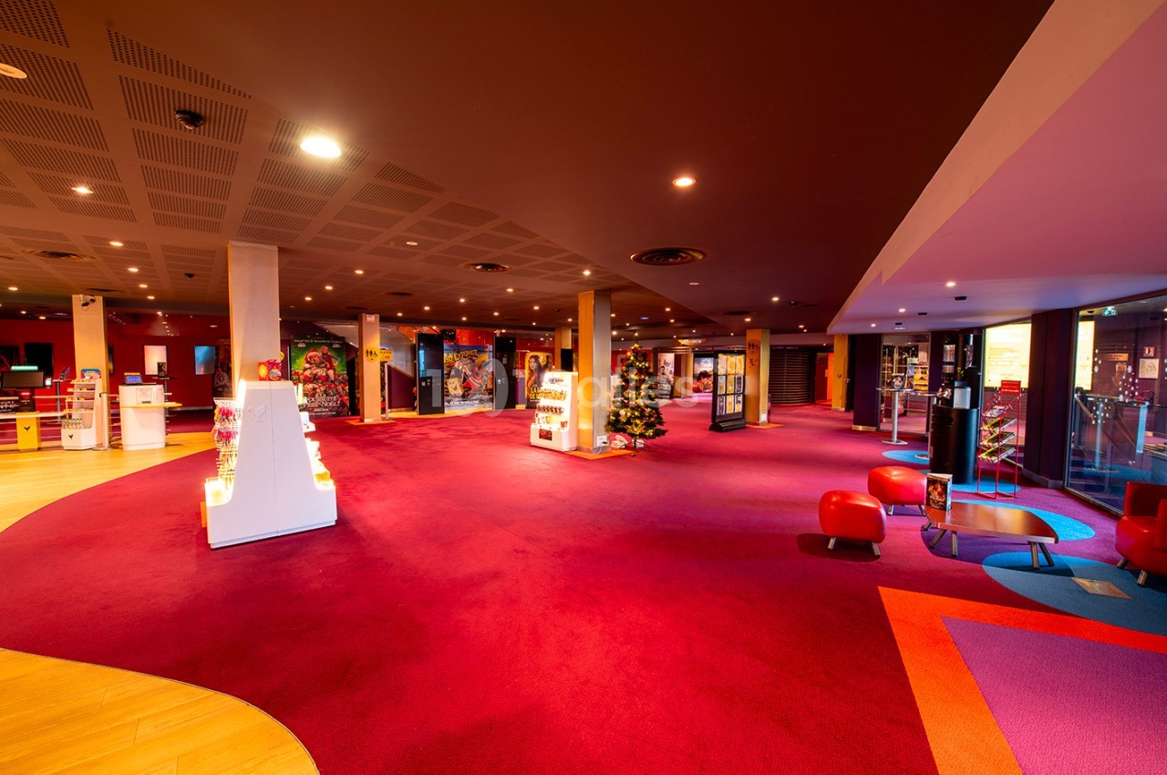 Espace intérieur lumineux avec moquette rouge, présentoirs blancs et décorations colorées dans un cadre moderne.