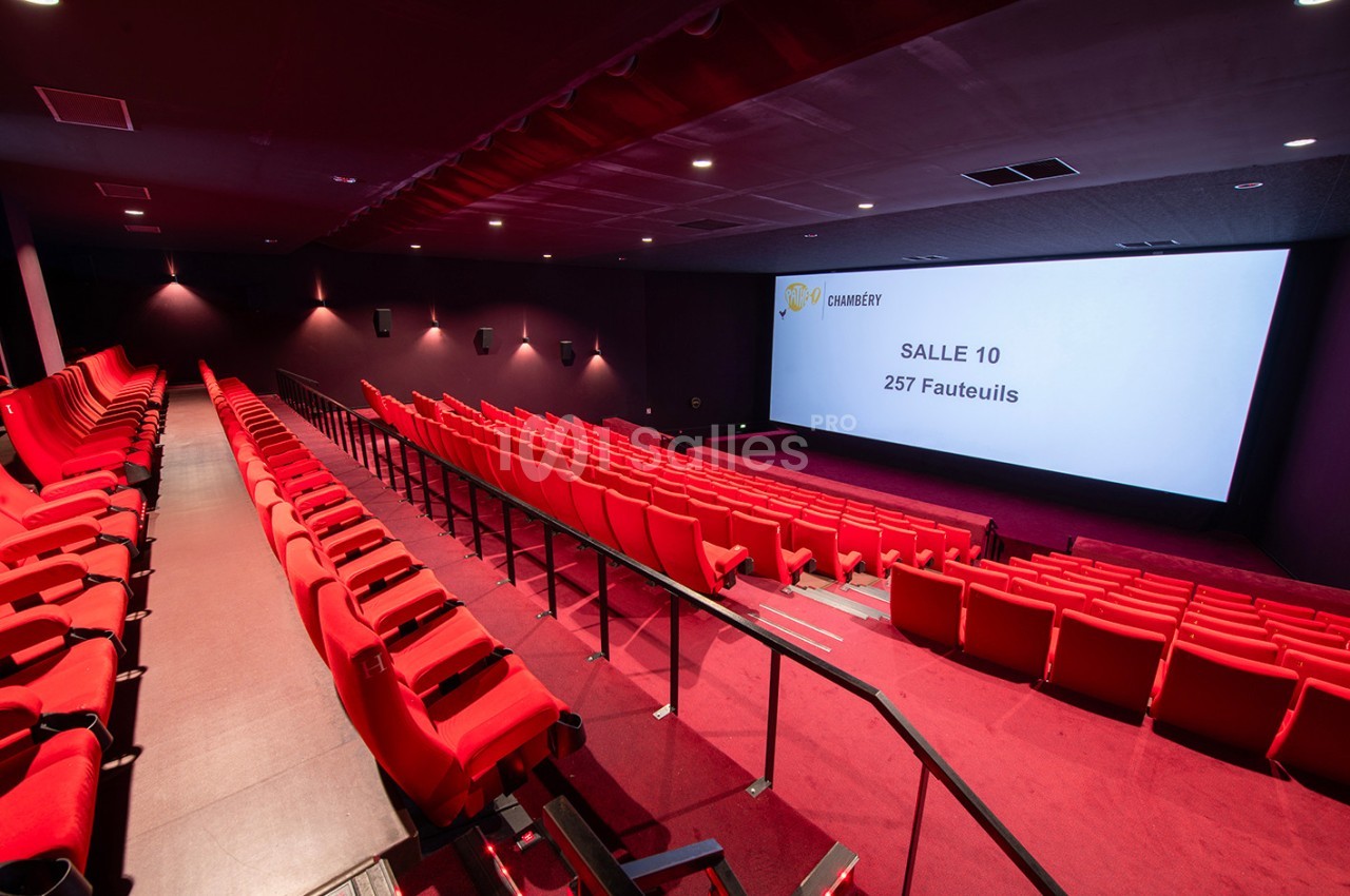 Salle de cinéma vide avec des rangées de fauteuils rouges et un écran affichant ’Salle 10, 257 fauteuils’.