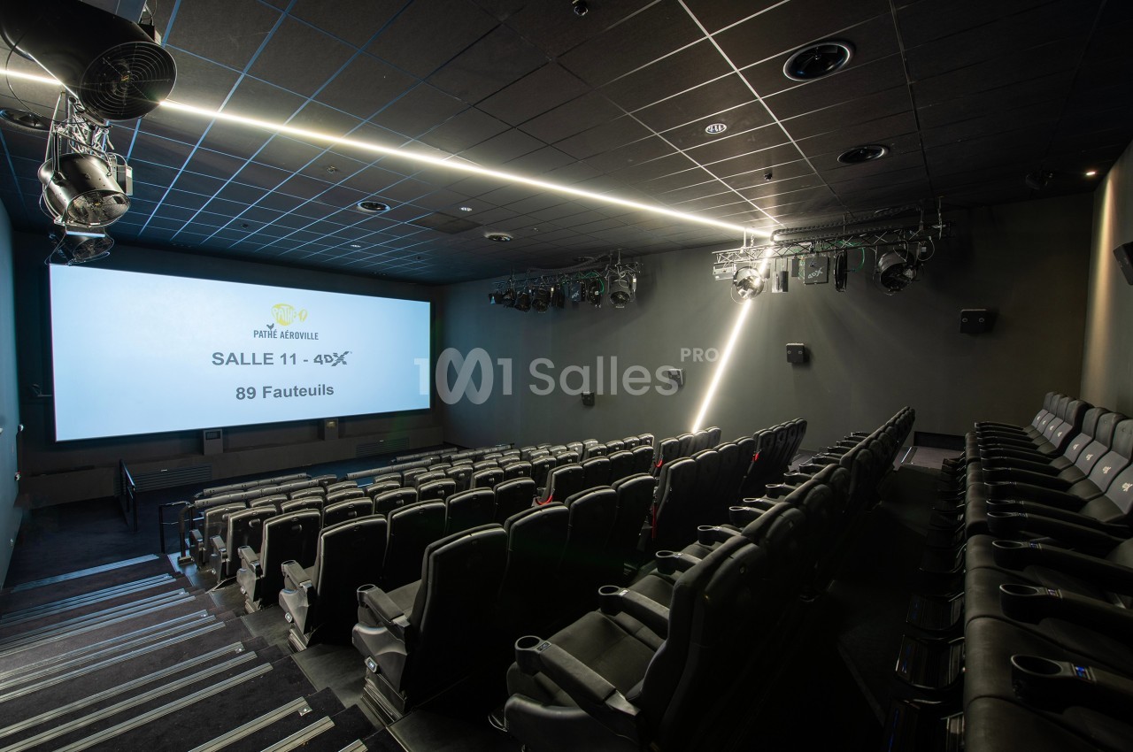 Salle de cinéma vide avec rangées de fauteuils noirs, écran allumé affichant ’Salle 411 - 4DX, 89 fauteuils’.
