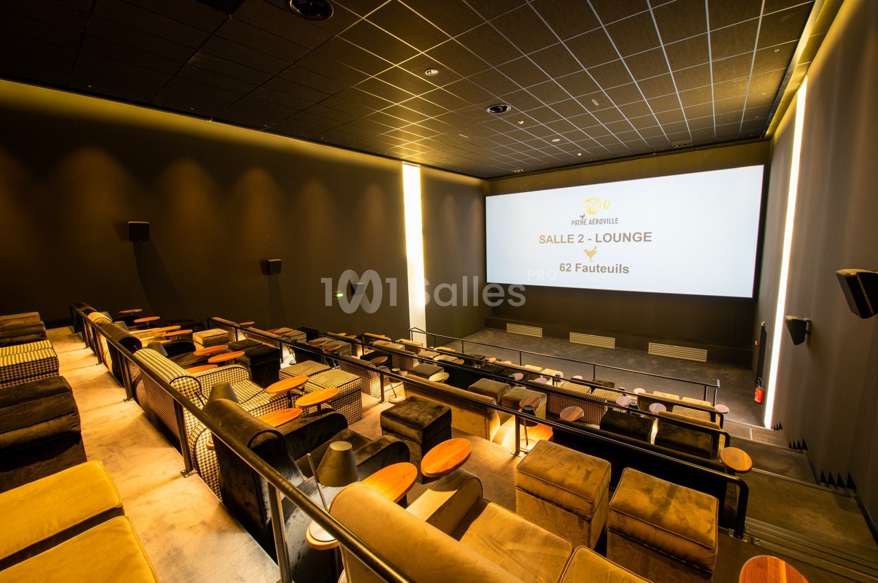 Salle de cinéma moderne avec fauteuils confortables, tables individuelles et écran affichant ’Salle 2 - Lounge’.