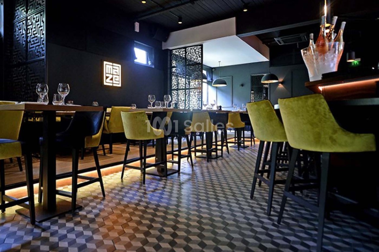 Salle de restaurant moderne avec chaises colorées, tables dressées et éclairage tamisé.