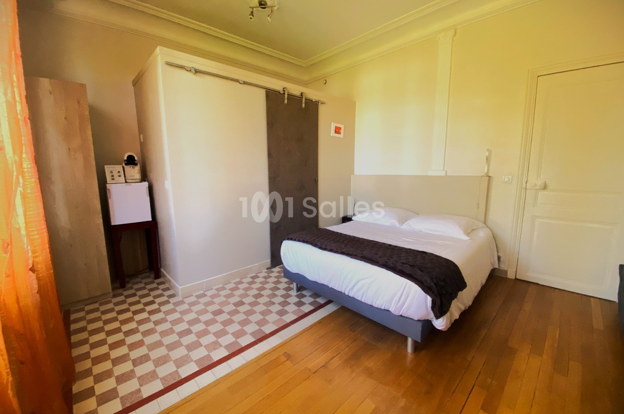 Chambre avec lit double, parquet, salle d'eau attenante avec porte coulissante et lumière naturelle.