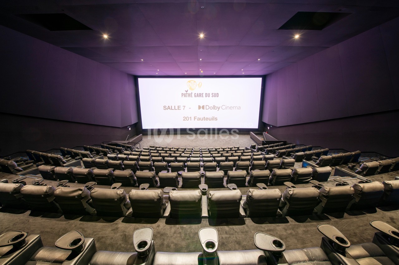 Salle de cinéma moderne avec grand écran, sièges inclinables en cuir et allée centrale.