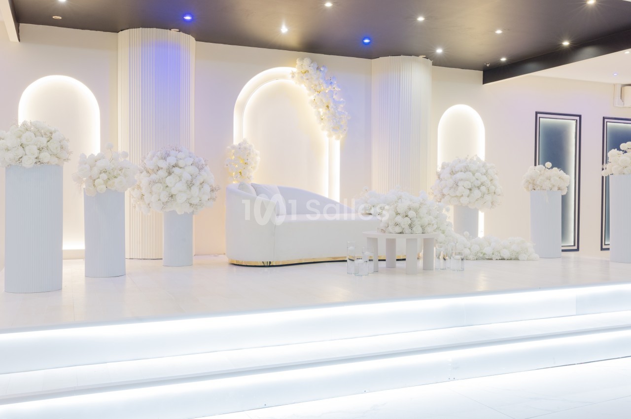 Décor lumineux et élégant avec un canapé blanc entouré de colonnes et de bouquets de fleurs blanches.
