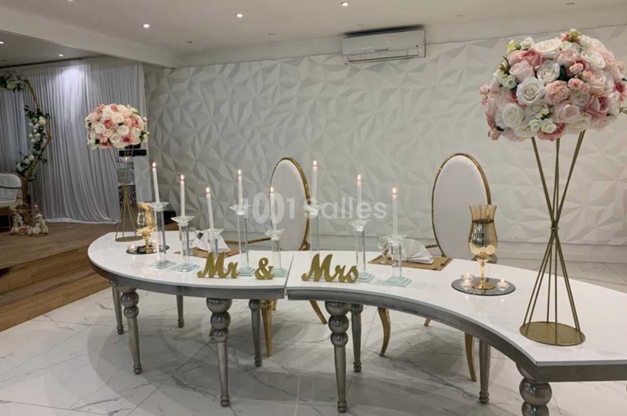 Table décorée pour un mariage avec chandeliers, fleurs roses et blanches, et inscriptions ’Mr & Mrs’ dorées.