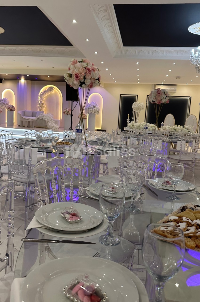 Salle de réception élégante avec tables dressées, décorations florales et éclairage tamisé.