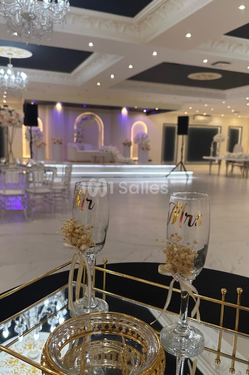 Deux flûtes gravées ’Mr’ posées sur une table décorative dans une salle de réception élégante et lumineuse.