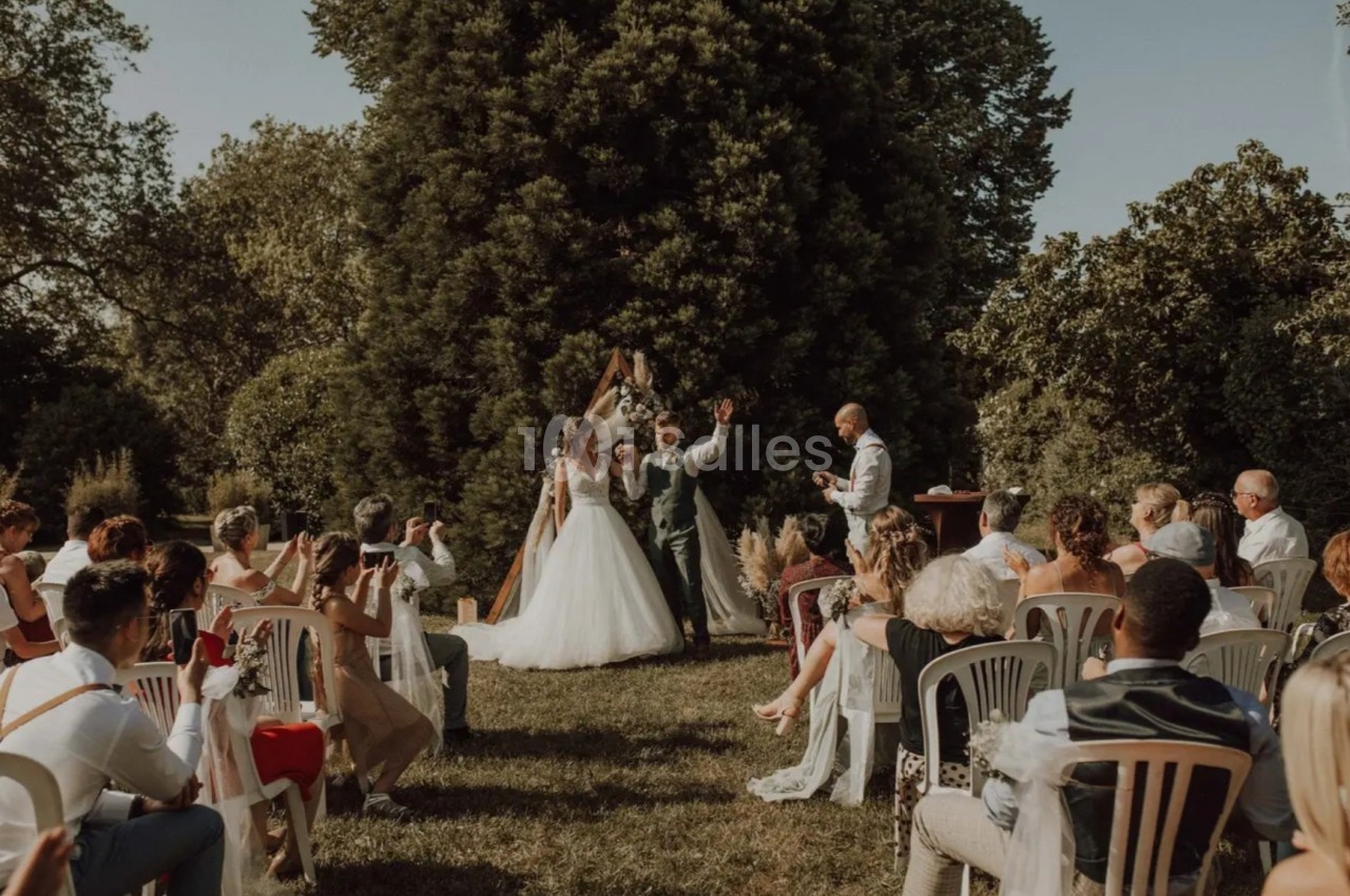 Cérémonie de mariage en plein air avec des invités assis, un couple échangeant ses vœux devant un officiant.