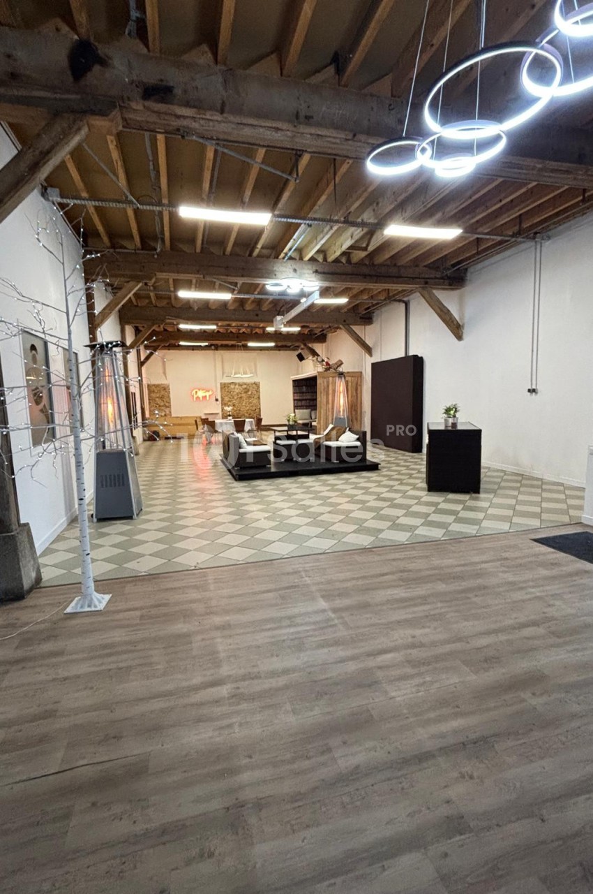 Espace intérieur spacieux avec plafond en bois, sol carrelé et parquet, mobilier moderne et éclairage design.
