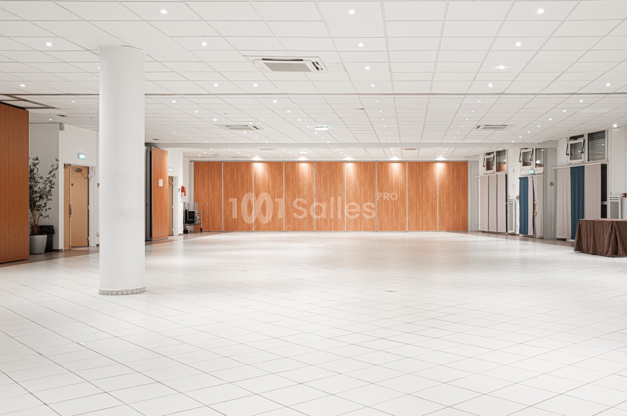 Salle spacieuse avec carrelage blanc, murs en bois clair, plafond à dalles et éclairage encastré.