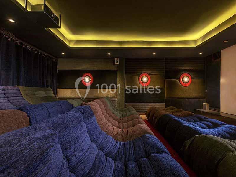 Salle de cinéma privée avec sièges inclinés en velours coloré, éclairage tamisé et murs insonorisés.