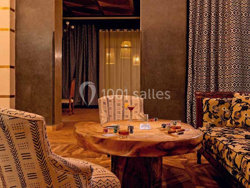 Table basse en bois entourée de fauteuils et d'un canapé aux motifs géométriques dans une pièce chaleureusement éclairée.