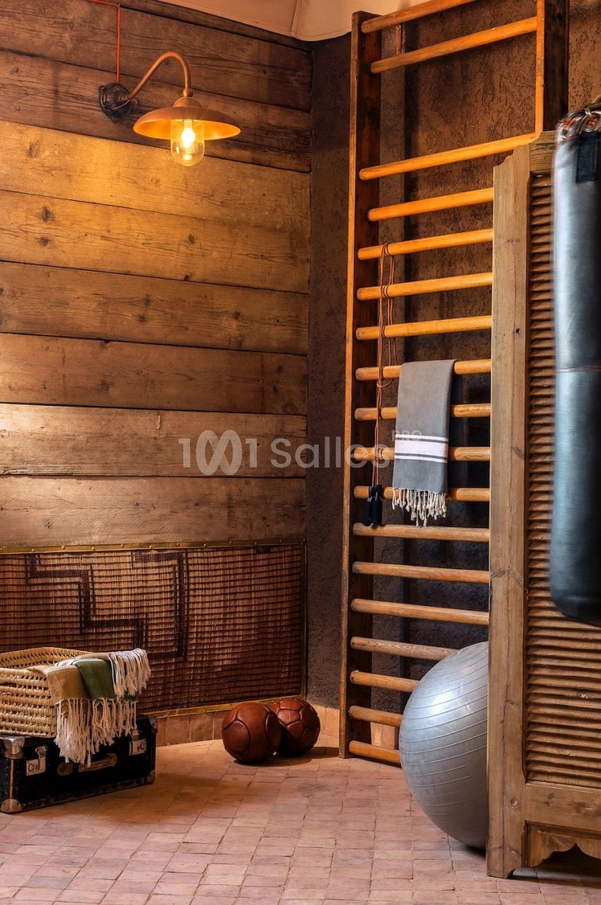 Salle de sport rustique avec espalier en bois, ballon d'exercice, punching-ball et accessoires de fitness.
