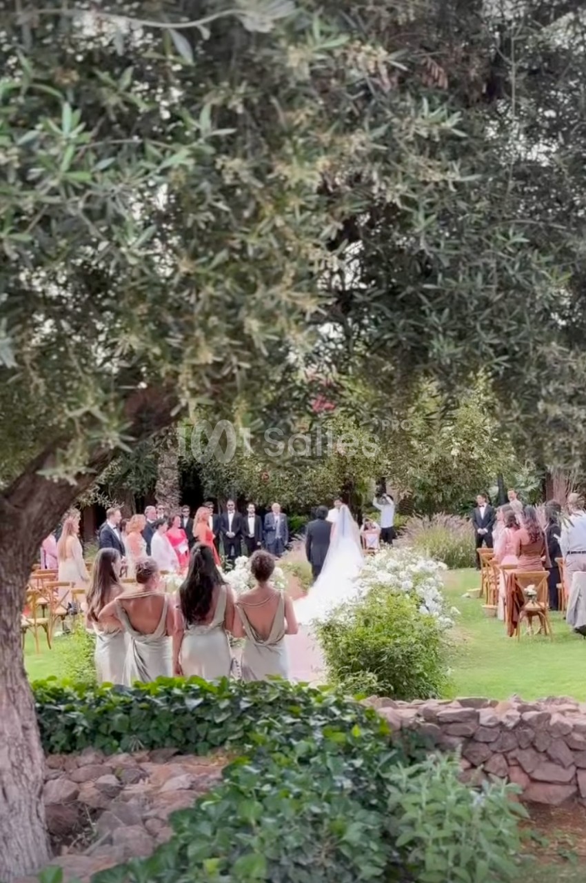 Cérémonie de mariage en plein air avec des invités debout autour des mariés dans un jardin verdoyant.