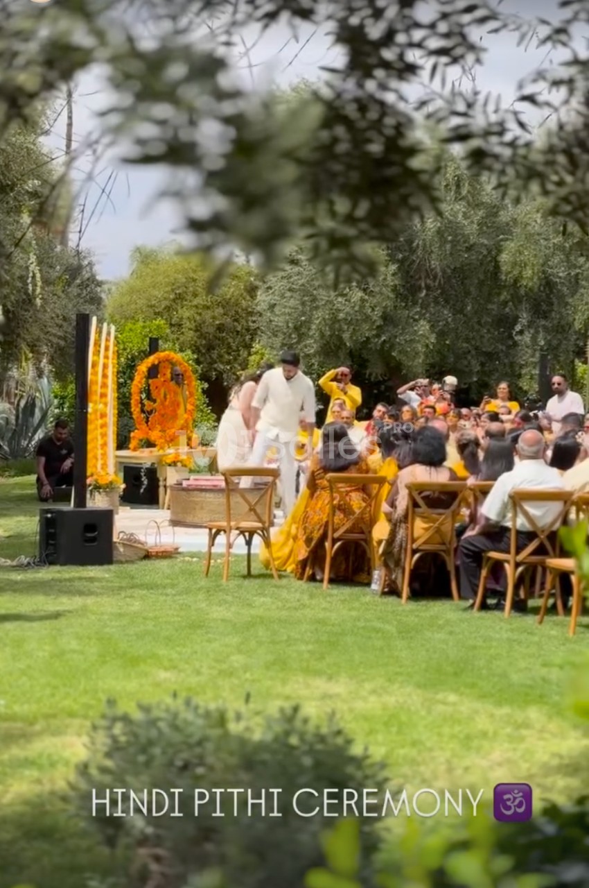 Un couple participe à une cérémonie hindoue en plein air, entouré d'invités assis et de décorations traditionnelles.