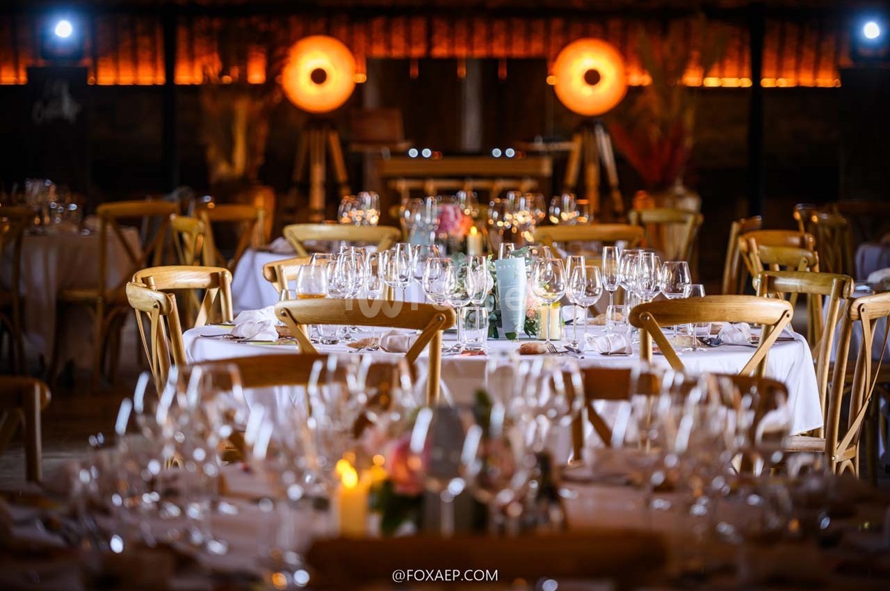 Salle de réception décorée avec des tables élégamment dressées, éclairée par des lumières chaudes et tamisées.