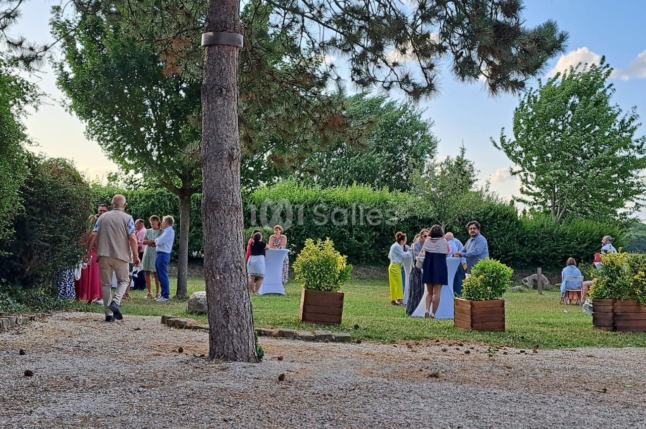 Groupe de personnes discutant debout dans un jardin arboré par une journée ensoleillée.