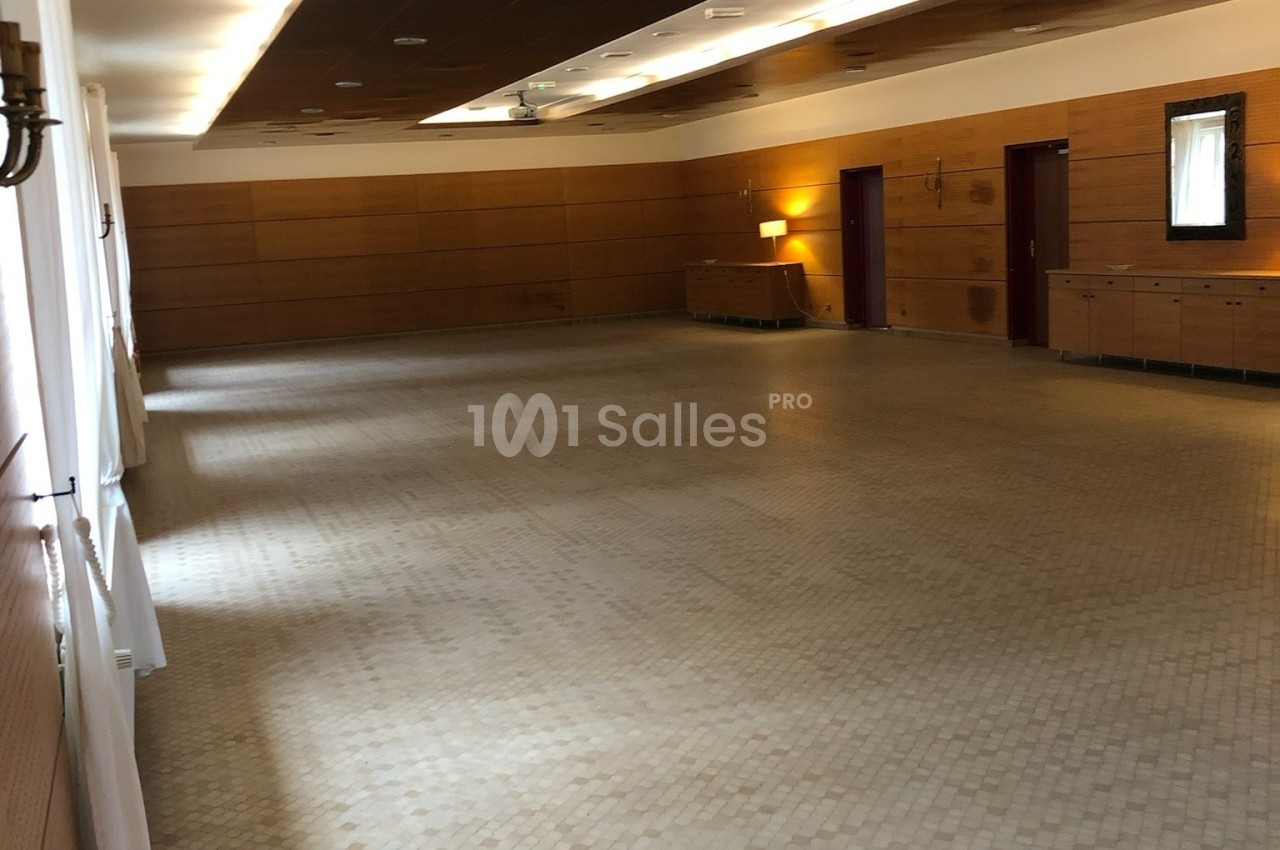 Salle vide avec sol en carrelage clair, murs en bois, éclairage tamisé et mobilier minimaliste.