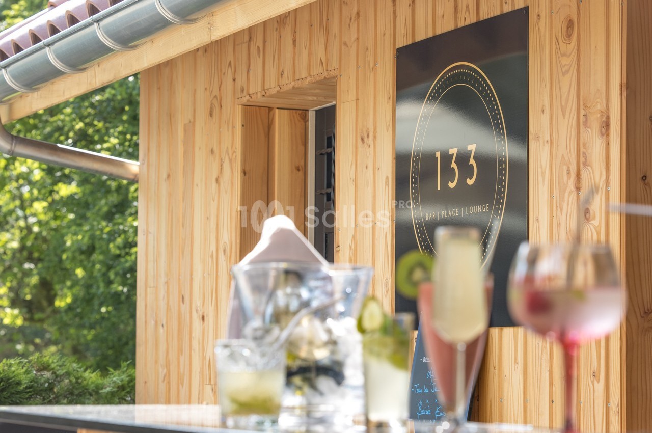 Boissons fraîches sur une table en bois devant un bâtiment en bois avec une enseigne ’133’.