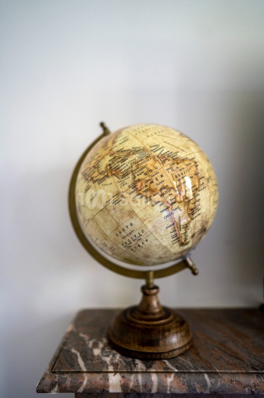 Globe terrestre vintage posé sur une table en marbre, montrant une carte ancienne des continents.