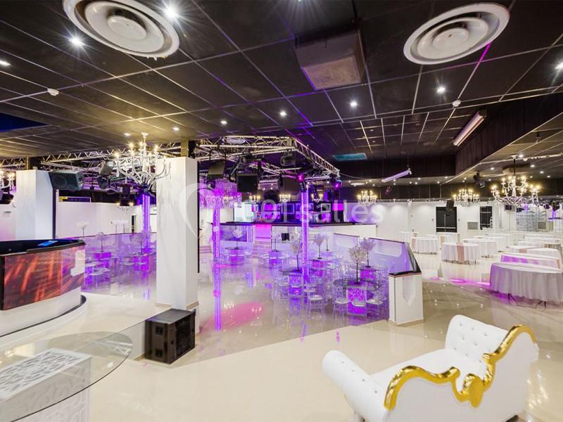 Salle de réception moderne avec éclairage violet, mobilier transparent et décorations élégantes.