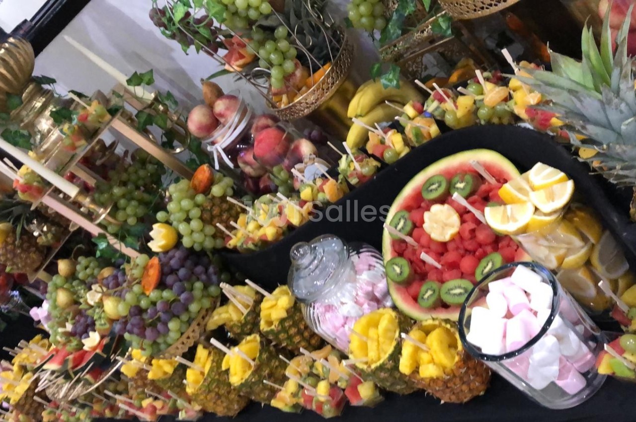 Buffet coloré de fruits frais comprenant pastèques, kiwis, raisins, ananas et brochettes de fruits variés.