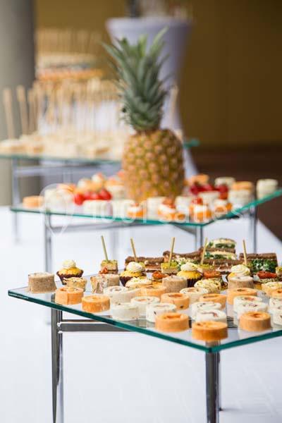 Buffet de bouchées apéritives variées présentées sur des plateaux en verre, avec un ananas en décoration centrale.