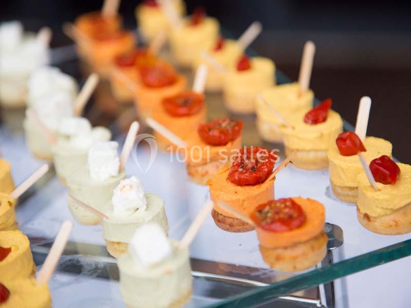 Assortiment de bouchées apéritives colorées sur des supports en verre, garnies de légumes et de fromage.