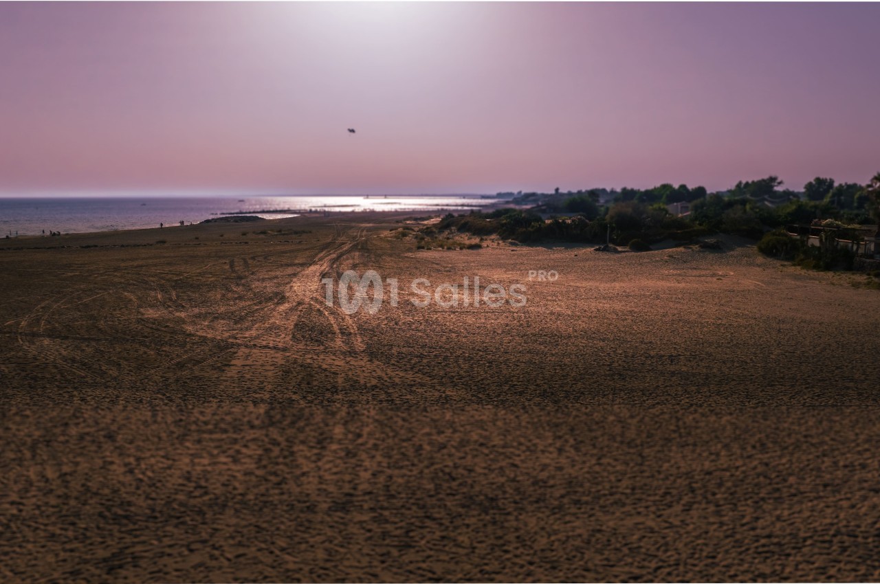 Plage déserte au coucher du soleil avec une lumière douce sur le sable et la mer à l'horizon.
