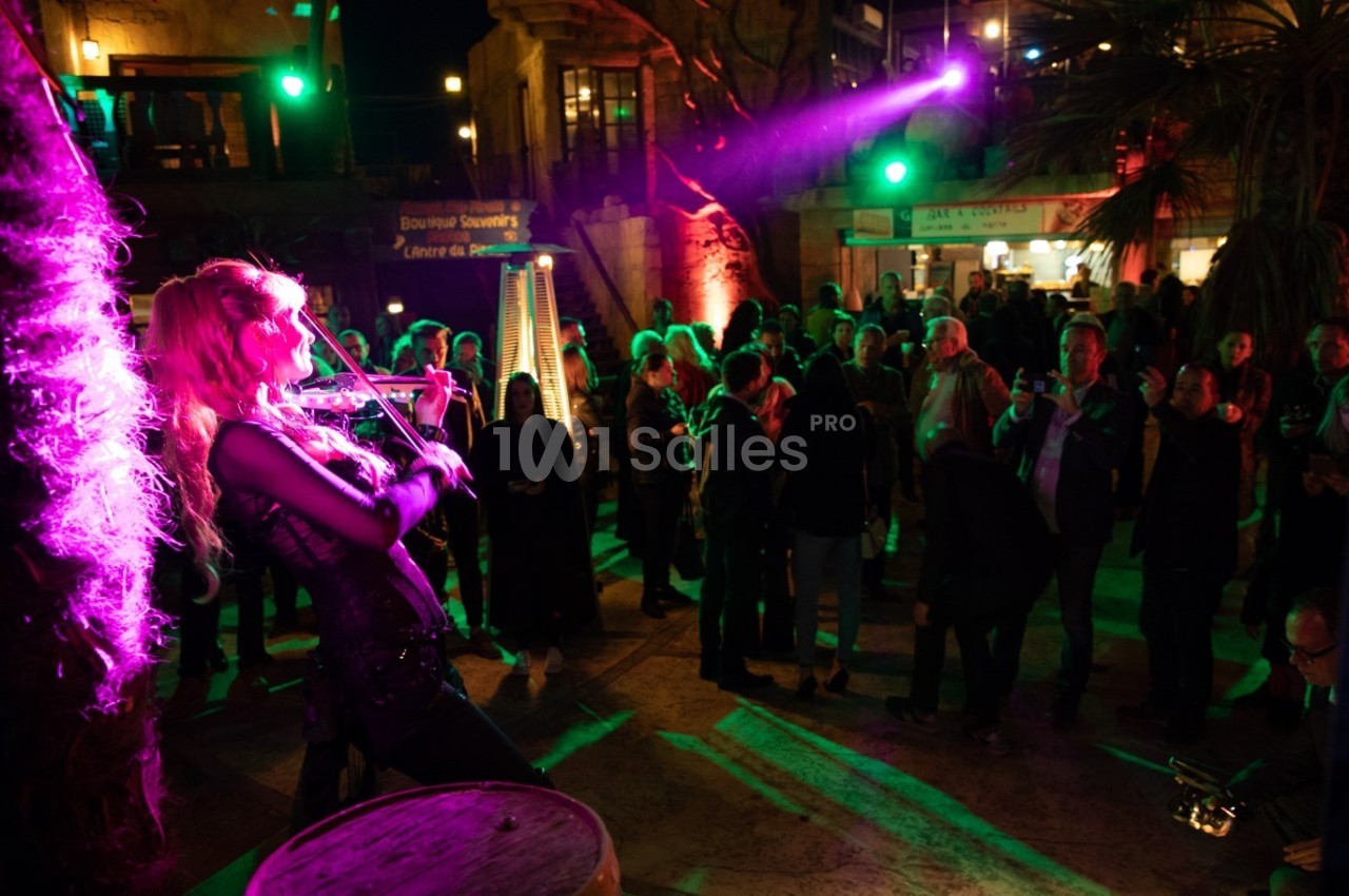 Une violoniste joue sur scène devant un public en soirée, éclairée par des lumières colorées.