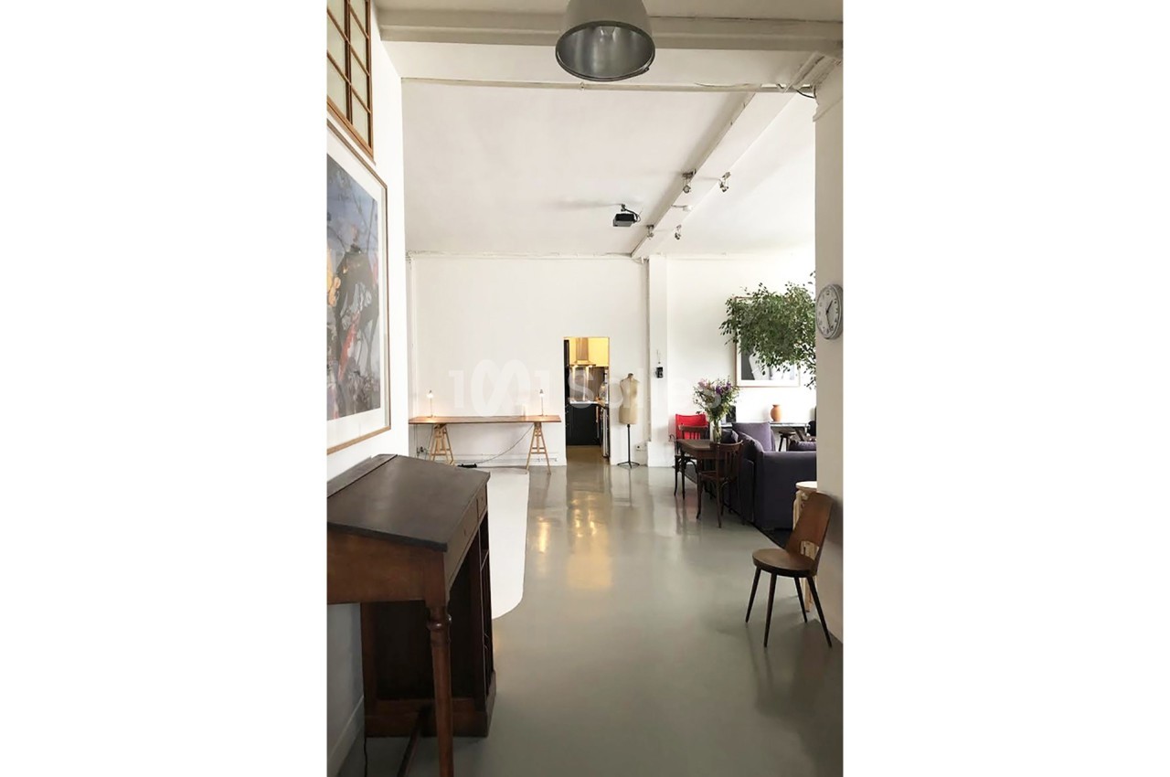 Intérieur lumineux avec mobilier minimaliste, plantes et un espace ouvert comprenant des tables et des chaises.