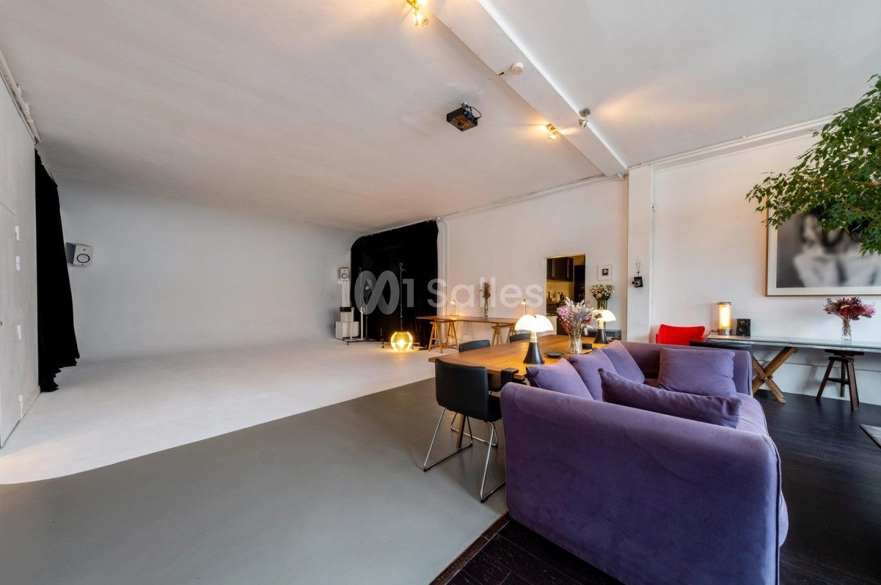Espace intérieur lumineux avec un studio photo, canapé violet, table en bois et décoration moderne.