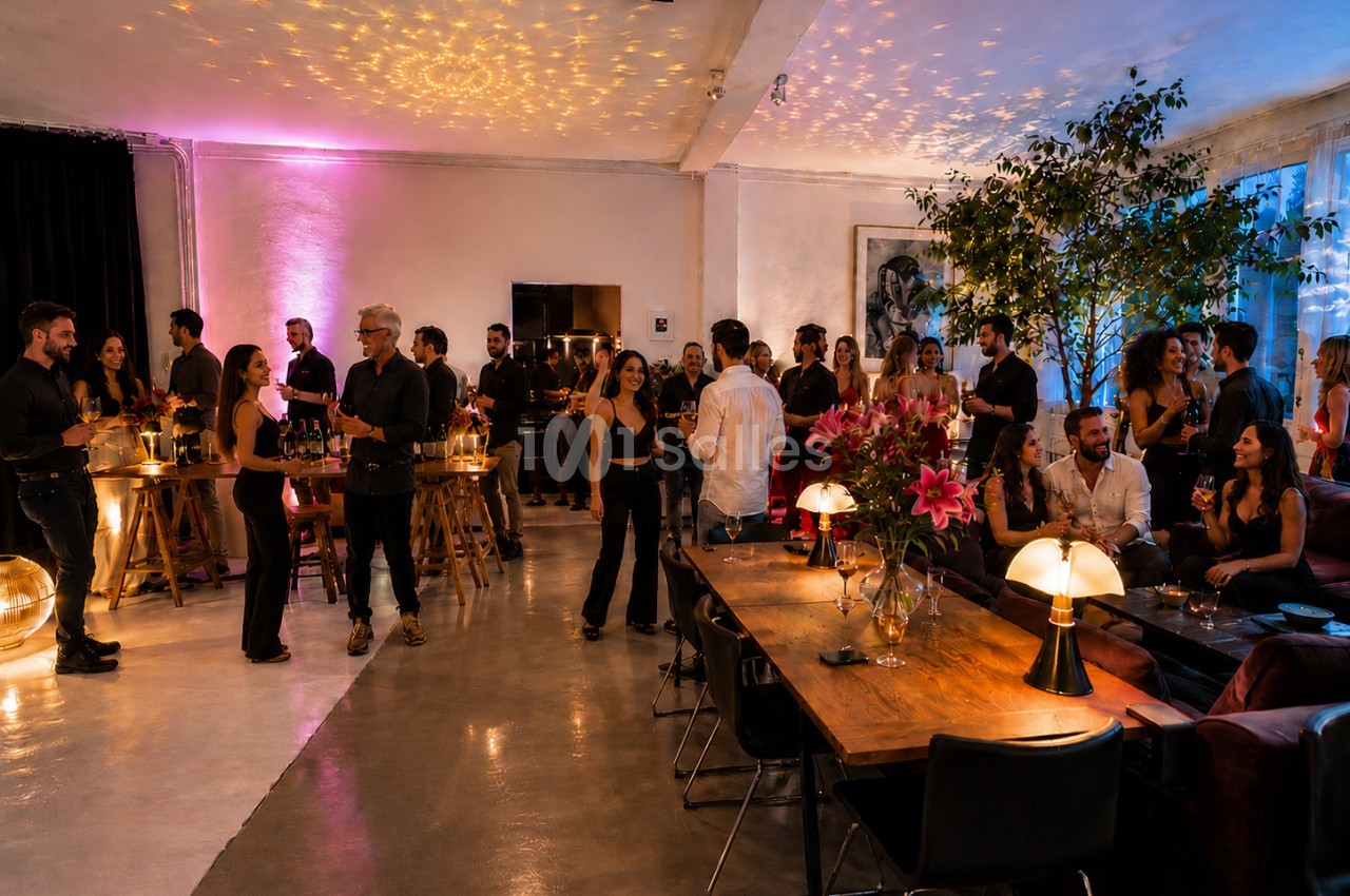 Personnes socialisant dans un espace intérieur élégant, éclairé par des lumières tamisées et décoré de fleurs et de plantes.