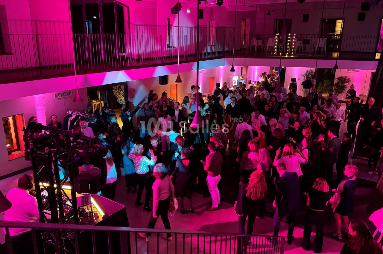 Groupe de personnes dans une salle éclairée par des lumières roses, rassemblées autour d'une piste de danse.