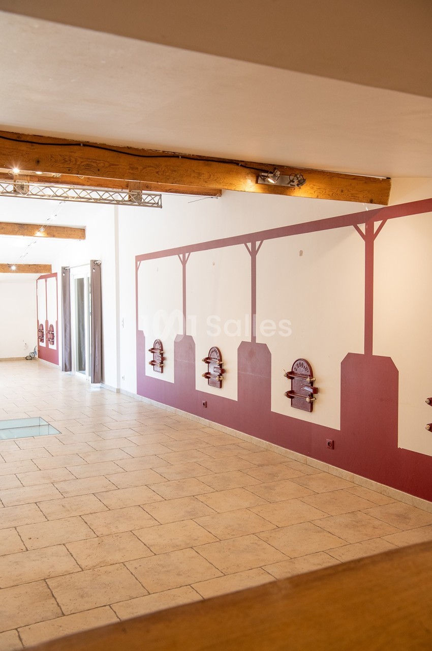 Mur intérieur avec décorations murales rouges, sol en carrelage beige et poutres apparentes au plafond.
