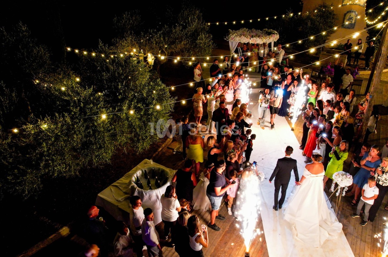 Vue aérienne d'une réception de mariage en soirée avec des guirlandes lumineuses et des invités entourant les mariés.