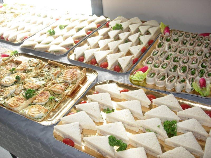 Plateaux de sandwichs variés, roulés et toasts garnis, présentés pour un buffet ou un événement.