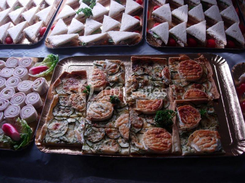 Plateaux de quiches aux légumes, sandwichs triangulaires et rondelles d'oignons disposés pour un buffet.