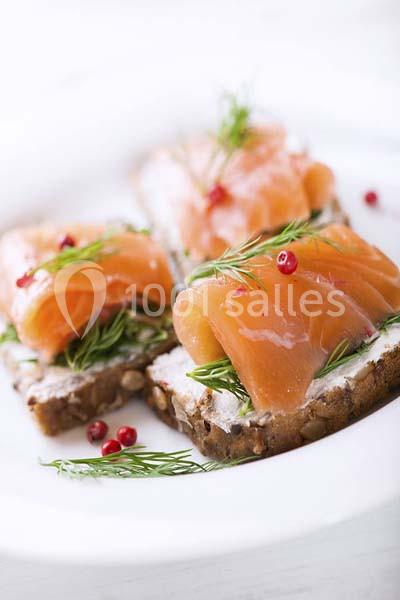 Tranches de saumon fumé sur du pain aux céréales avec fromage frais, aneth et baies roses.